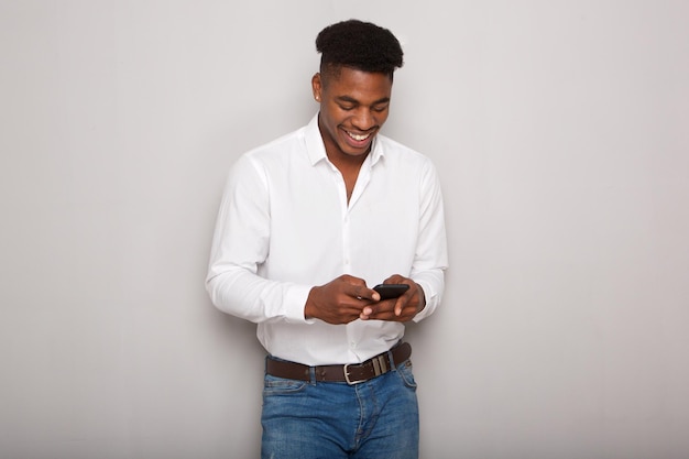 Un jeune Africain souriant regarde son téléphone portable en arrière-plan.