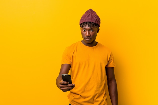 Jeune, africaine, debout, contre, jaune, mur, chapeau, utilisation, téléphone