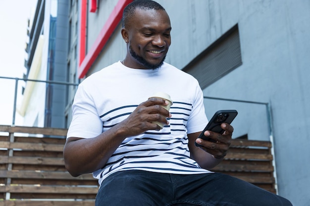 Un jeune afro-américain élégant avec un kwa et un smartphone dans les mains