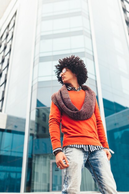 Jeune afro-américain noir bouclé avec des lunettes se promène dans la ville