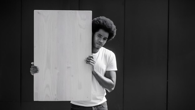 Un jeune Afro-Américain se cachant derrière un tableau blanc.