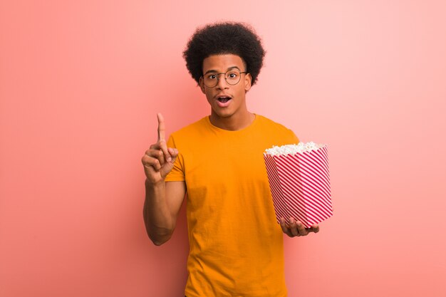 Jeune afro-américain tenant un seau à pop-corn ayant une excellente idée, concept de créativité