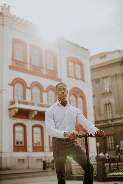 Jeune afro-américain utilisant un scooter électrique dans une rue