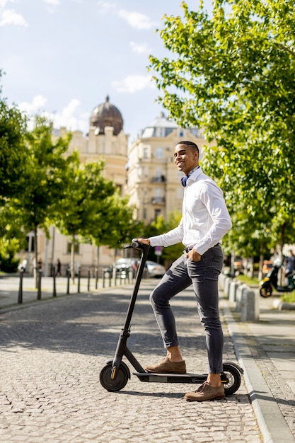 Jeune afro-américain utilisant un scooter électrique dans une rue