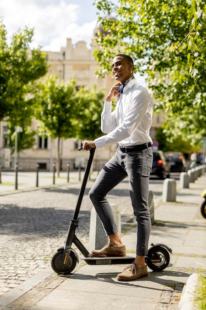 Jeune afro-américain utilisant un scooter électrique dans une rue