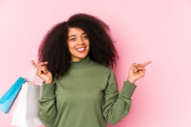 Jeune, afro, femme, achats, isolé jeune, afro, femme, achat, isolaYoung, afro, femme, tenue, a, roses, isolé, sourire, et, pointage côté, montrer, quelque chose, à, espace vide. <Mixto>