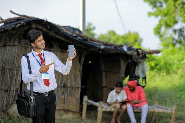 Jeune agent de banque indienne montrant écran mobile avec agriculteur