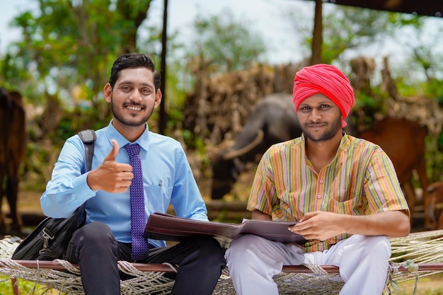 Jeune agent de banque indienne remplissant des papiers avec un agriculteur de sa ferme.