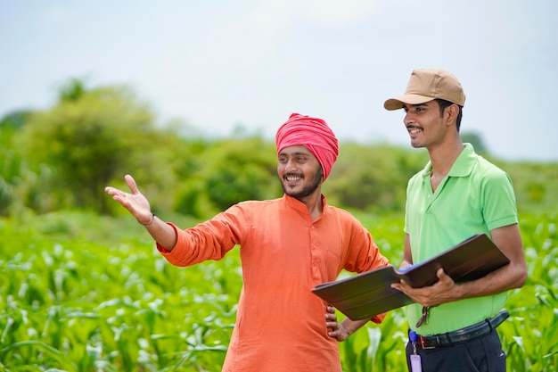 Jeune agent de banque indienne remplissant des papiers avec des agriculteurs dans un domaine agricole.