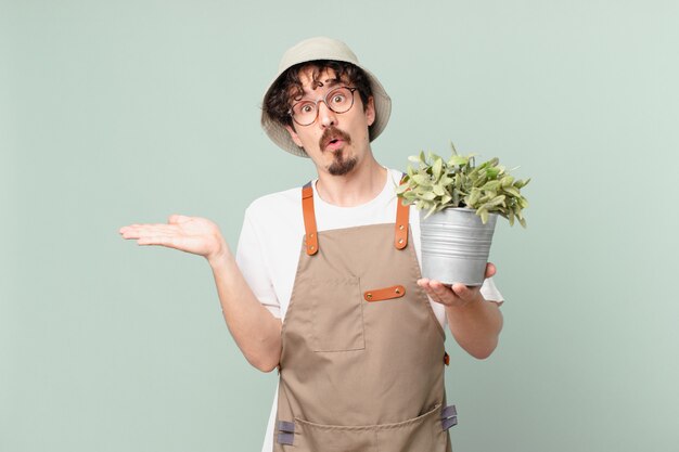 jeune agriculteur à l'air surpris et choqué, avec la mâchoire tombée tenant un objet