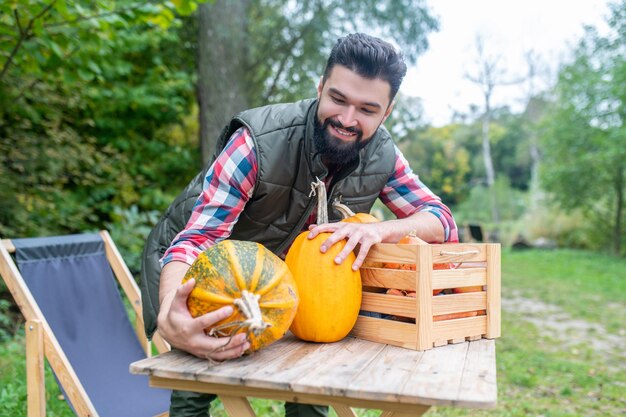 Un jeune agriculteur aux cheveux noirs avec des citrouilles à content