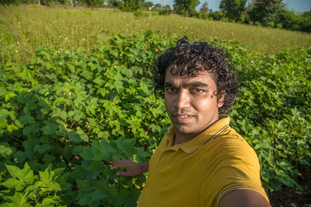 Jeune agriculteur dans une ferme de coton prenant selfie à l'aide d'un smartphone ou d'un appareil photo.