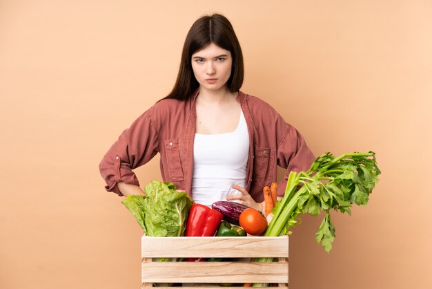 Jeune agriculteur femme avec des légumes fraîchement cueillis dans une boîte en colère