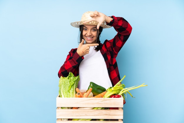 Jeune agriculteur Femme tenant des légumes frais dans un panier en bois se concentrant sur le visage. Symbole d'encadrement