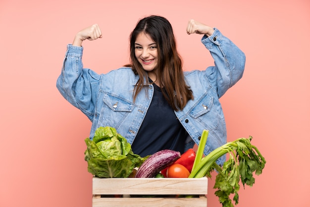 Jeune agriculteur femme tenant un panier plein de légumes frais célébrant une victoire