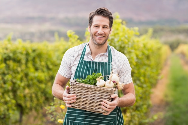 Jeune agriculteur heureux tenant un panier de légumes