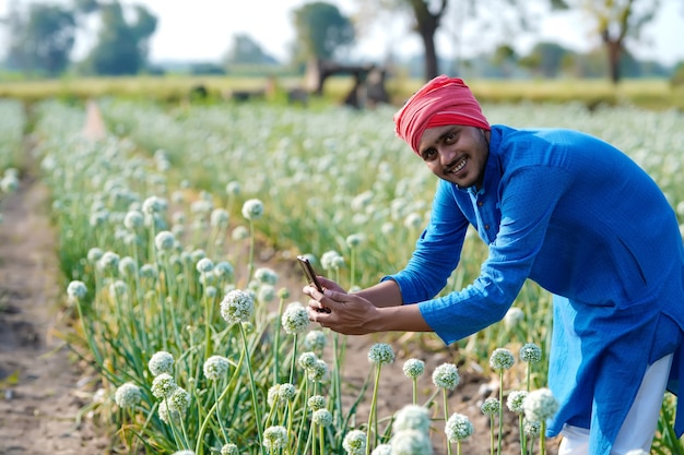 Jeune agriculteur indien à l'aide de smartphone au domaine de l'agriculture