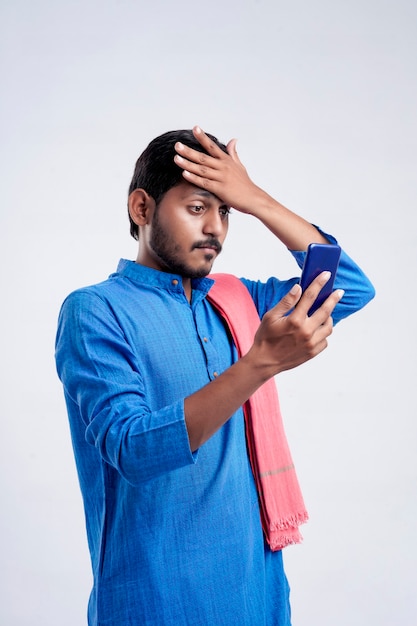 Jeune agriculteur indien choquant et stressé Après l'enregistrement du smartphone sur fond blanc.