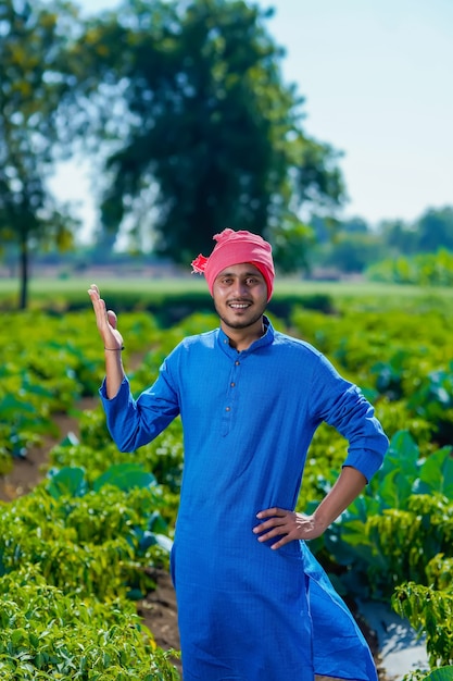 Jeune agriculteur indien debout au champ frisquet vert