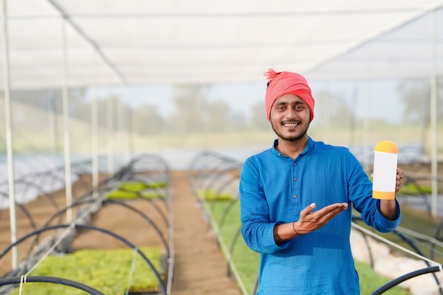 Jeune agriculteur indien montrant une bouteille d'engrais à effet de serre