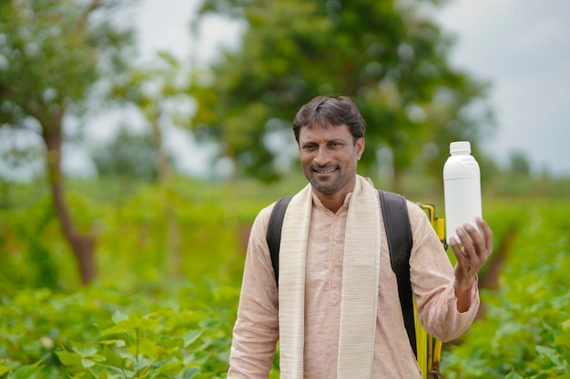 Jeune Agriculteur Indien Montrant Une Bouteille D'engrais Liquide Sur Le Terrain De L'agriculture.