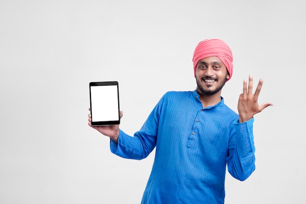 Jeune agriculteur indien montrant une tablette et donnant une expression sur fond blanc.