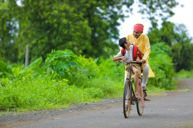 Jeune agriculteur indien et son fils vont à l'école sur cycle