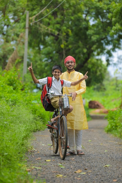 Jeune agriculteur indien et son fils vont à l'école sur cycle