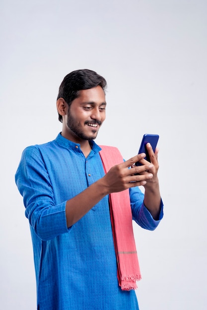Jeune agriculteur indien utilisant un smartphone sur fond blanc.