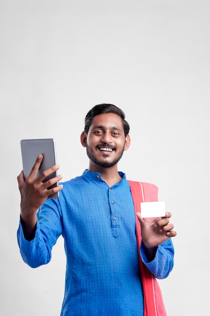 Jeune agriculteur indien utilisant une tablette et donnant une expression sur fond blanc.