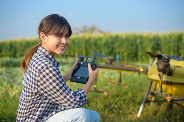 Un jeune agriculteur intelligent contrôlant la pulvérisation d'engrais et de pesticides par un drone sur les terres agricoles