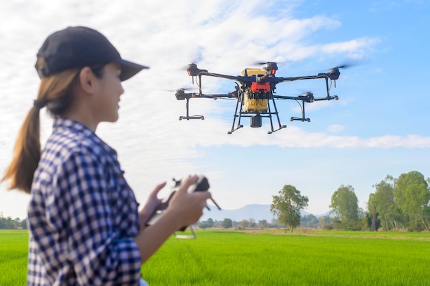 Un jeune agriculteur intelligent contrôlant la pulvérisation d'engrais et de pesticides par un drone sur les terres agricoles