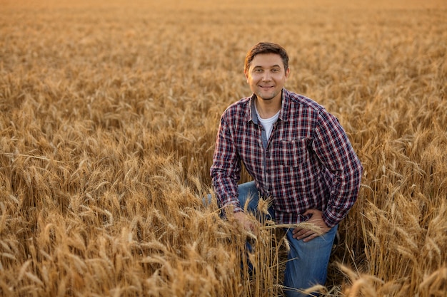 Jeune agriculteur satisfait avec un tas de blé mûr