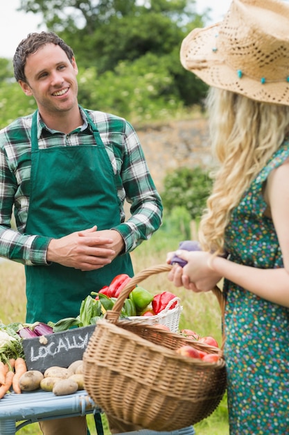 Jeune agriculteur vendant des légumes biologiques à jolie blonde