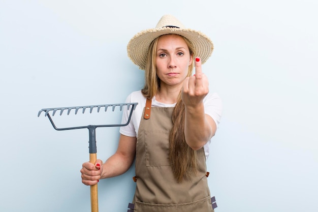 Jeune agricultrice blonde adulte avec un râteau