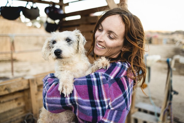 Jeune agricultrice jouant avec son chien au ranch de la ferme - Focus sur le visage féminin