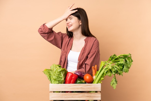 Jeune agricultrice avec des légumes fraîchement cueillis dans une boîte a réalisé quelque chose et a l'intention de la solution