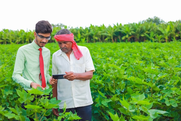 Jeune agronome et agriculteur inspectant le champ de coton avec tablette