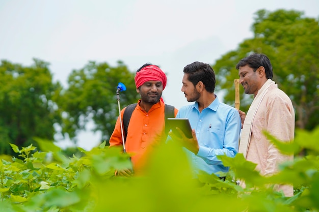 Jeune agronome ou banquier indien montrant des informations à l'agriculteur dans une tablette sur le terrain de l'agriculture.