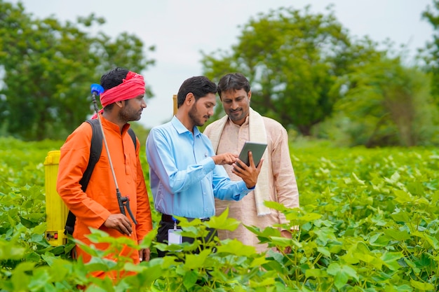 Jeune agronome ou banquier indien montrant des informations à l'agriculteur dans une tablette sur le terrain de l'agriculture.