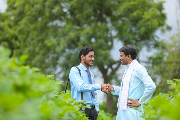 Un jeune agronome ou banquier indien serre la main d'un agriculteur dans un domaine agricole.