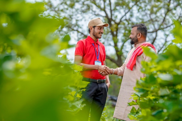 Un jeune agronome ou banquier indien serre la main d'un agriculteur dans un domaine agricole.