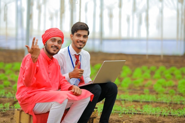 Jeune Agronome Indien Montrant Des Informations à L'agriculteur Dans Un Ordinateur Portable à Effet De Serre