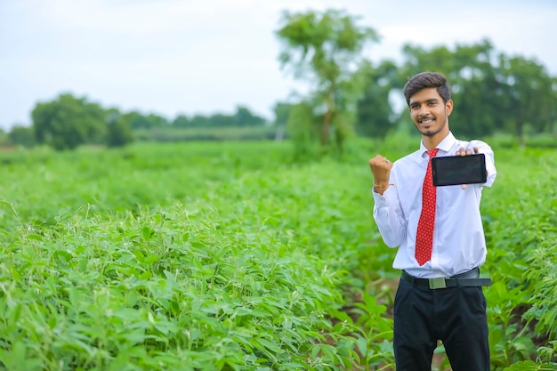 Jeune agronome indien montrant smartphone au champ