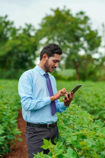 Jeune agronome ou officier indien utilisant une tablette sur le terrain agricole.