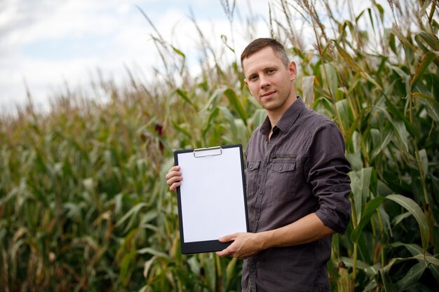 Le jeune agronome tient une carte papier dans ses mains et analyse la récolte de maïs