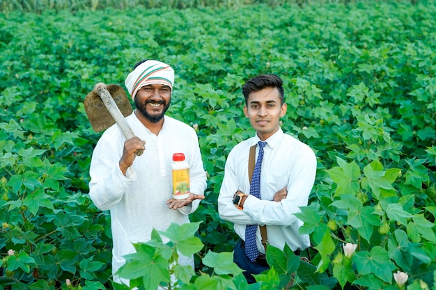 Photo un jeune agronomiste indien donne une bouteille d'engrais liquide à un agriculteur dans un champ d'agriculture verte