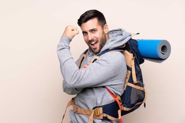 Jeune alpiniste avec un gros sac à dos faisant un geste fort