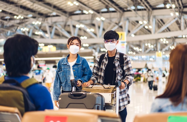 Photo jeune ami voyageur heureux en quarantaine pour coronavirus portant un masque chirurgical protection du visage détiennent un passeport et un billet avant un long vol de vacances à l'aéroport international