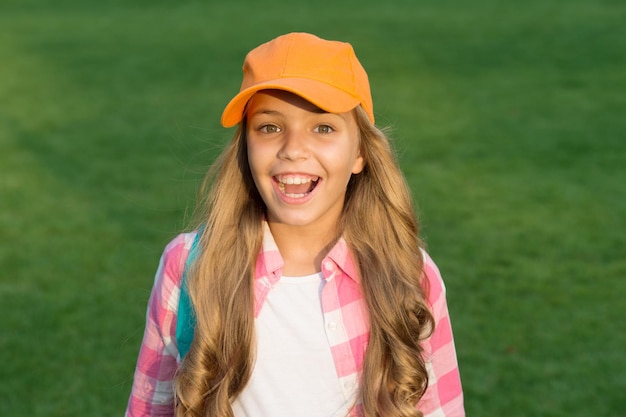 Jeune et amusant. Enfant heureux sur l'herbe verte. Petite fille dans un style décontracté. Vêtements décontractés cool pour les enfants. Vêtement de rue. Accessoire de mode. Style et tendance. Garde-robe décontractée. Regard de beauté. L'air décontracté.